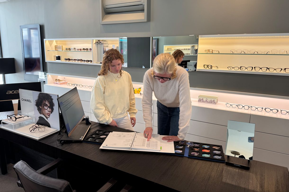 Caroline Pankert beugt sich über einen Katalog und zeigt Thea Cormann darin etwas