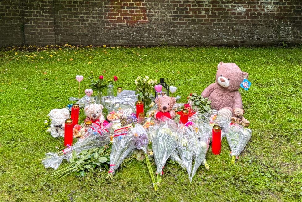 Teddys, Blumen und Kerzen liegen auf dem Rasen, wo sich die tödliche Schießerei ereignet hat