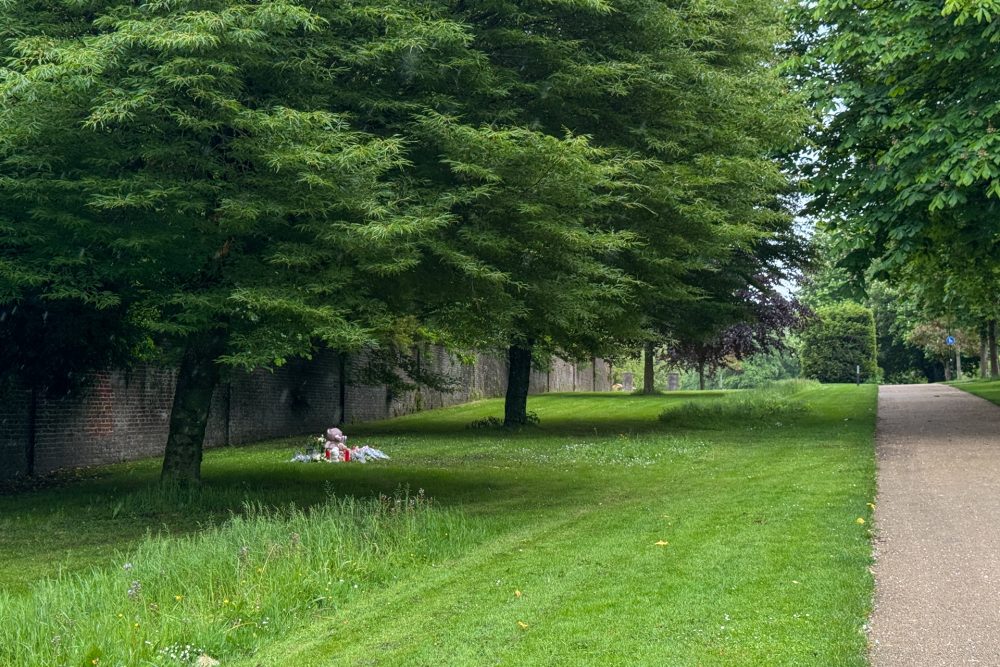 Links der Rasen, auf dem sich die Tat ereignet hat, mit hohen Bäumen, rechts ein Parkweg