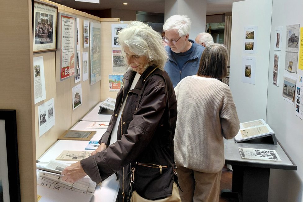 Ausstellungsbesucher schauen sich ausgestellte Dokumente an