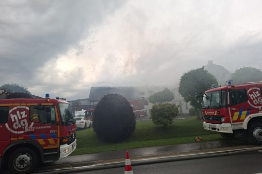 Mehrere Löschfahrzeuge stehen vor einem Gebäude, aus dem Rauch aufsteigt