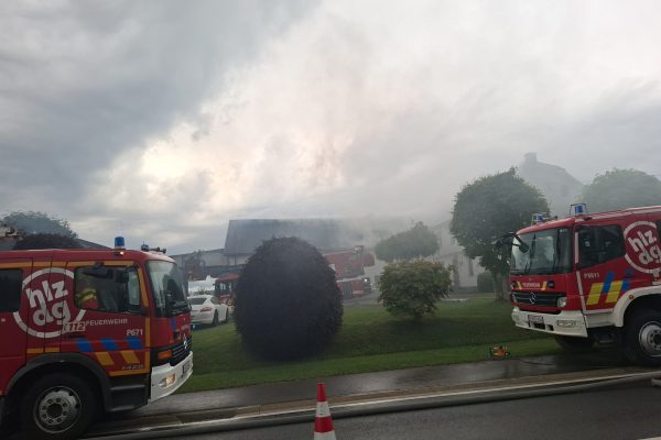 Mehrere Löschfahrzeuge stehen vor einem Gebäude, aus dem Rauch aufsteigt