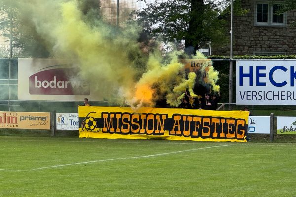 Banner mit der Aufschrift "Mission Aufstieg", dazu aufziehende gelbe Rauchschwaden