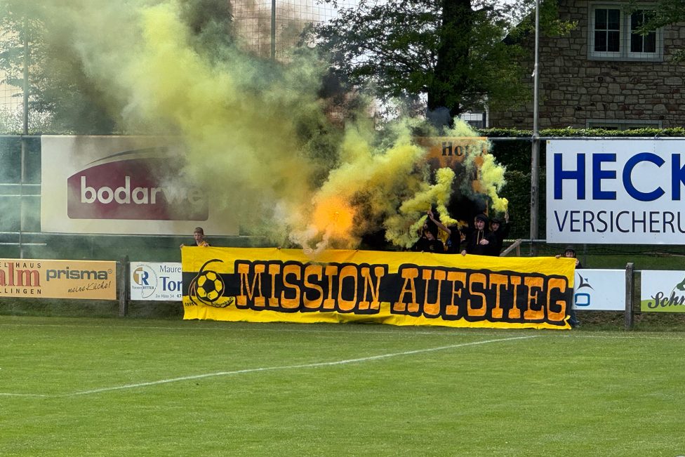 Banner mit der Aufschrift "Mission Aufstieg", dazu aufziehende gelbe Rauchschwaden