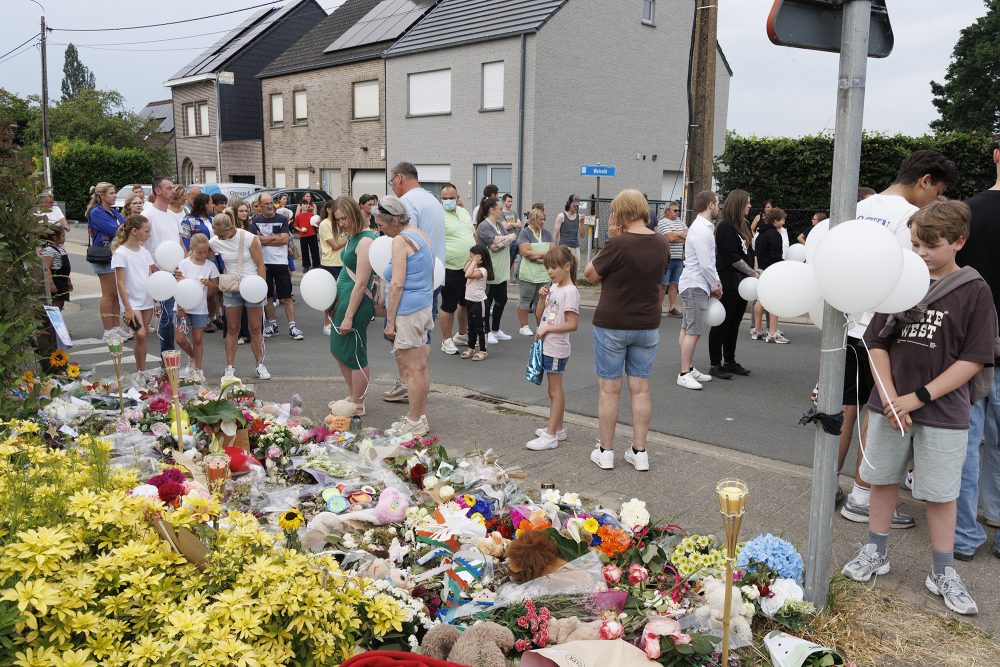 Menschen legen an der Unglücksstelle Blumen nieder und halten weiße Ballons in der Hand