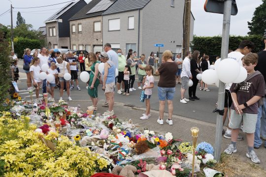 Menschen legen an der Unglücksstelle Blumen nieder und halten weiße Ballons in der Hand
