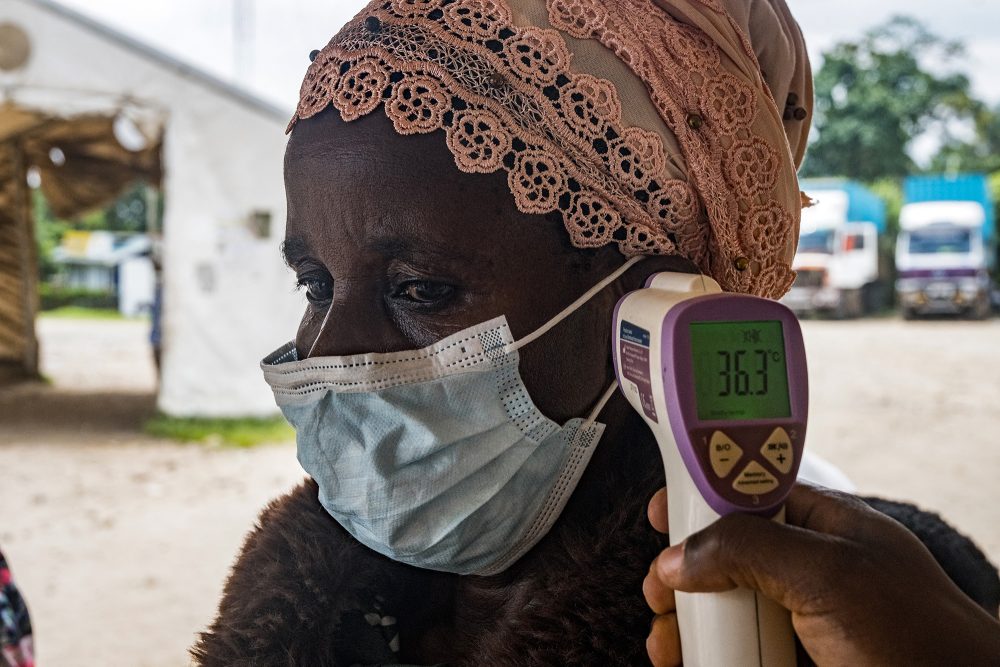 Bei einer Frau mit Mundschutz wird Fieber gemessen - als Vorsichtsmaßnahme wegen der Ausbreitung des Ebola-Virus