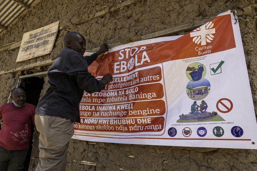 Ein Mann hängt ein Banner zur Aufklärung über Ebola auf