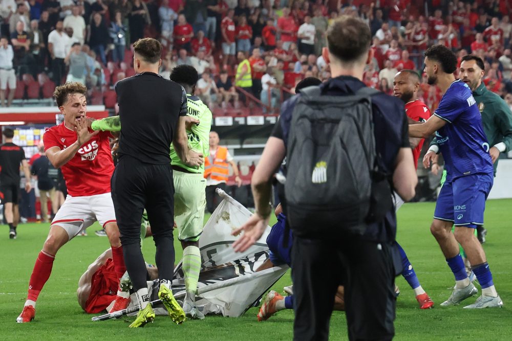 Spieler beider Vereine und Hooligans im Kampf miteinander auf dem Fußballfeld