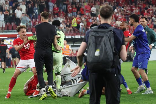 Spieler beider Vereine und Hooligans im Kampf miteinander auf dem Fußballfeld