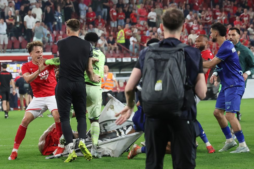 Spieler beider Vereine und Hooligans im Kampf miteinander auf dem Fußballfeld