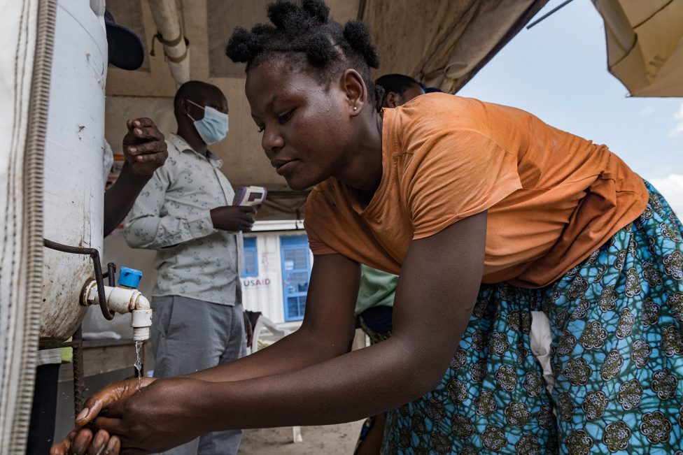 Kontrollposten an der Grenze zwischen Uganda und der DR Kongo in Busunga: Ein Mitarbeiter misst die Temperatur, eine Frau wäscht sich die Hände
