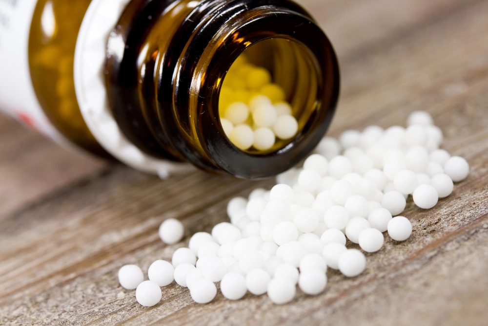 Homöopathie: Kügelchen liegen vor einem Behälter
