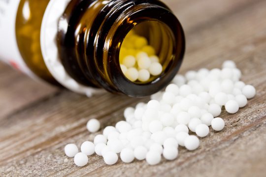 Homöopathie: Kügelchen liegen vor einem Behälter