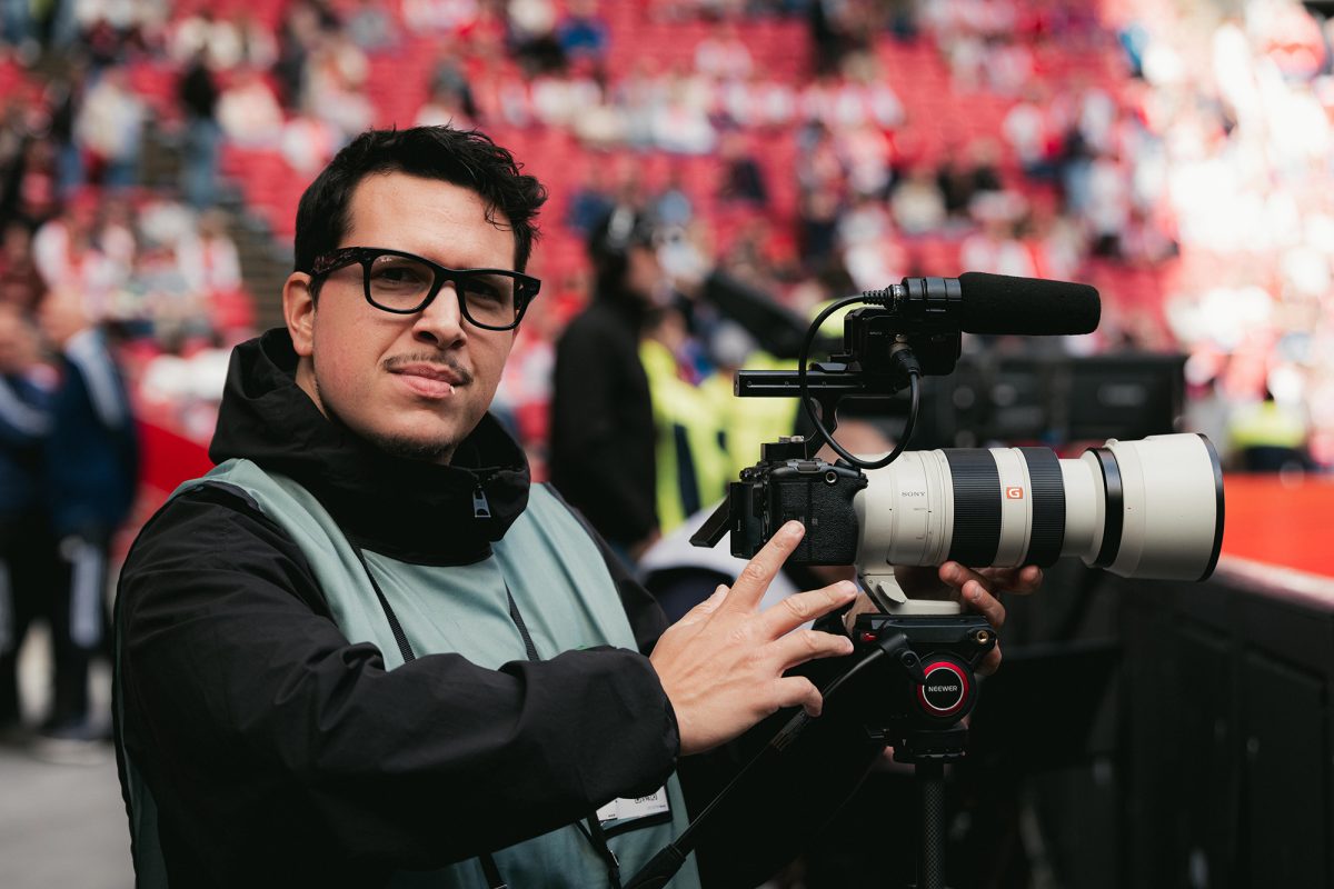 Jordi Fourgon steht neben einer Fotokamera in einem Stadion