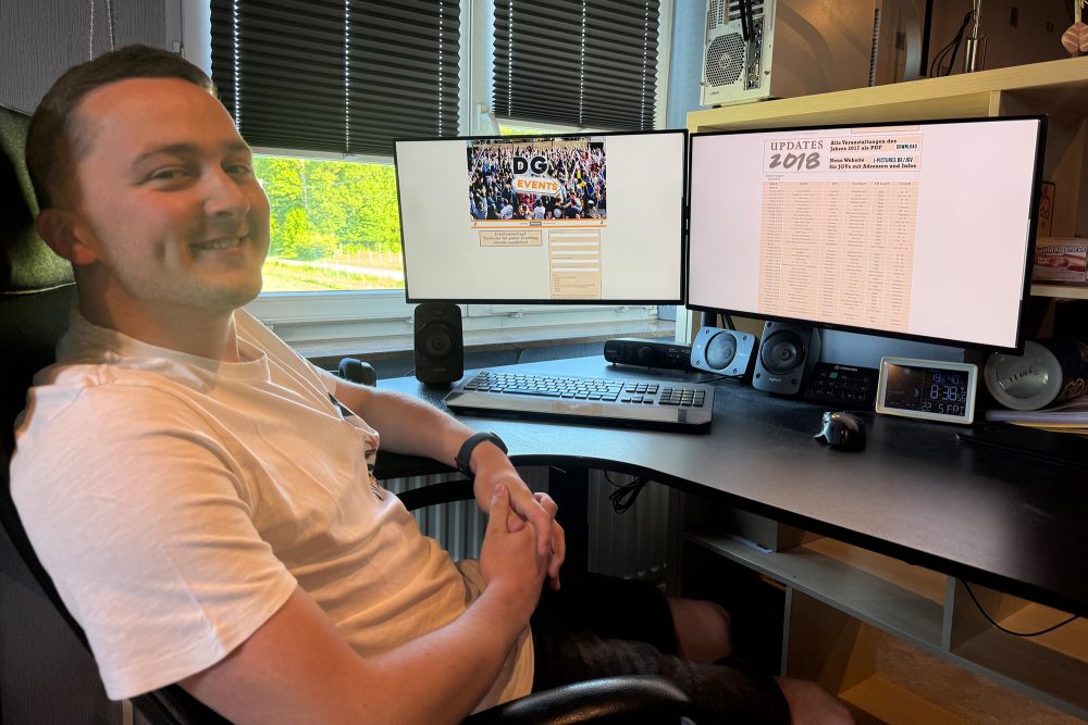 Julien Feltes sitzt am Schreibtisch, auf dem PC-Monitore stehen