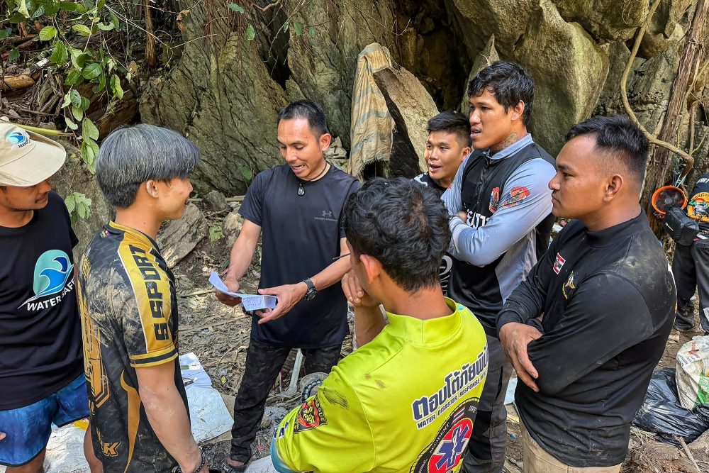 Retter bei einer Besprechung vor der Höhle, in der die Goldsucher eingeschlossen waren