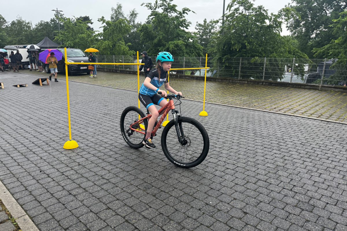 Kind fährt mit dem Fahrrad unter einer Barriere hindurch
