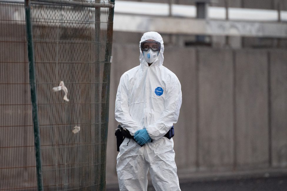 Ein Mitarbeiter des Zivilschutzes in Schutzkleidung mit Atemschutz steht im Hafengebiet