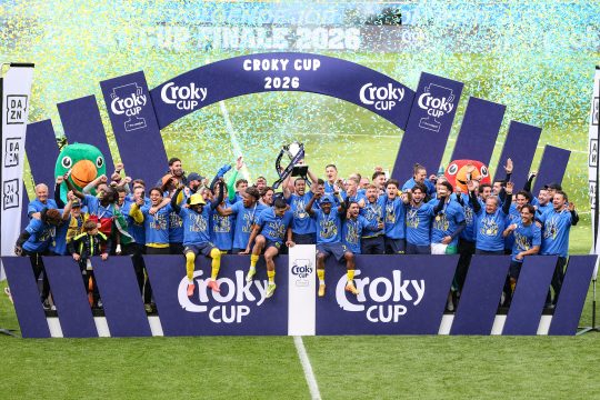 Spieler und Betreuerstab jubeln mit dem Pokal in ihrer Mitte