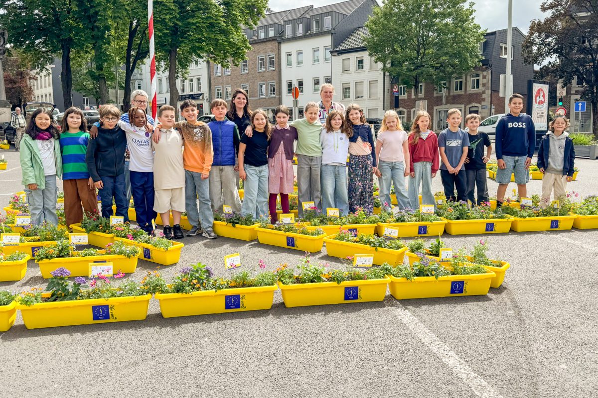 Mitwirkende des Projekts versammeln sich für ein Gruppenbild, davor stehen Blumenkästen auf dem Boden