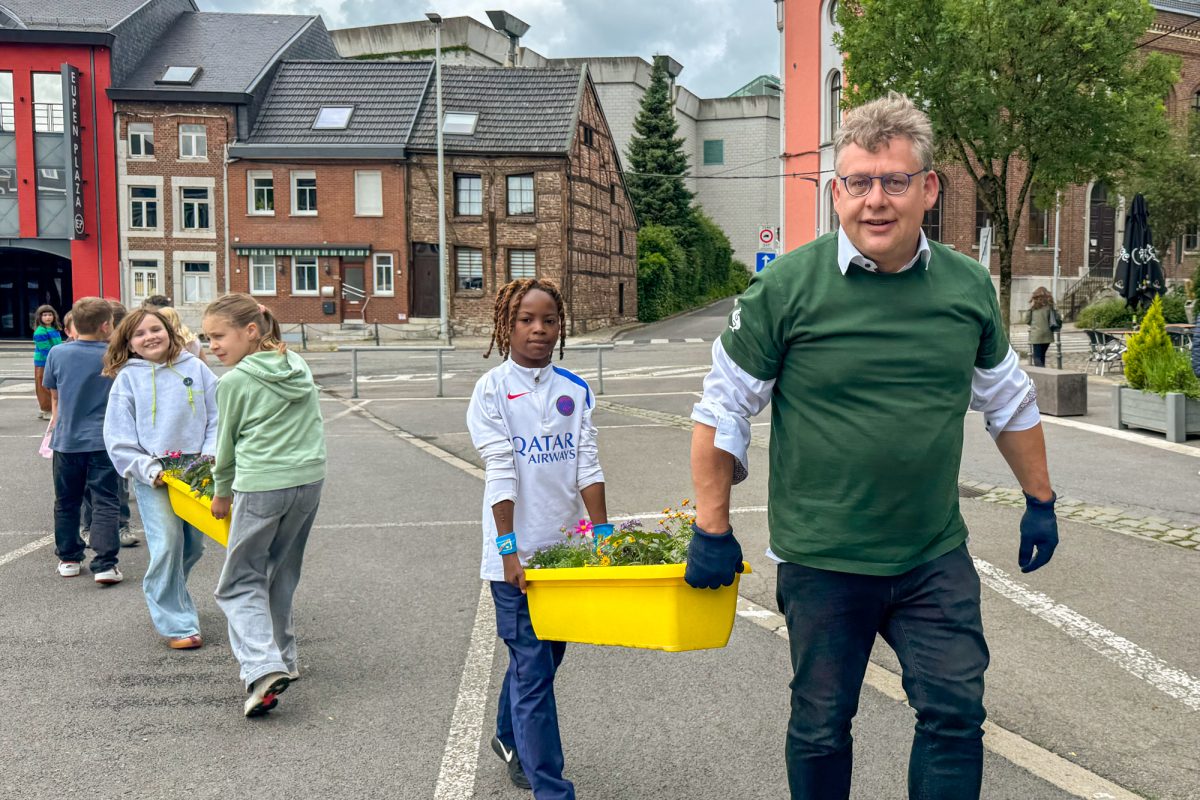 Ein Mann und mehrere Kinder tragen Blumenkästen