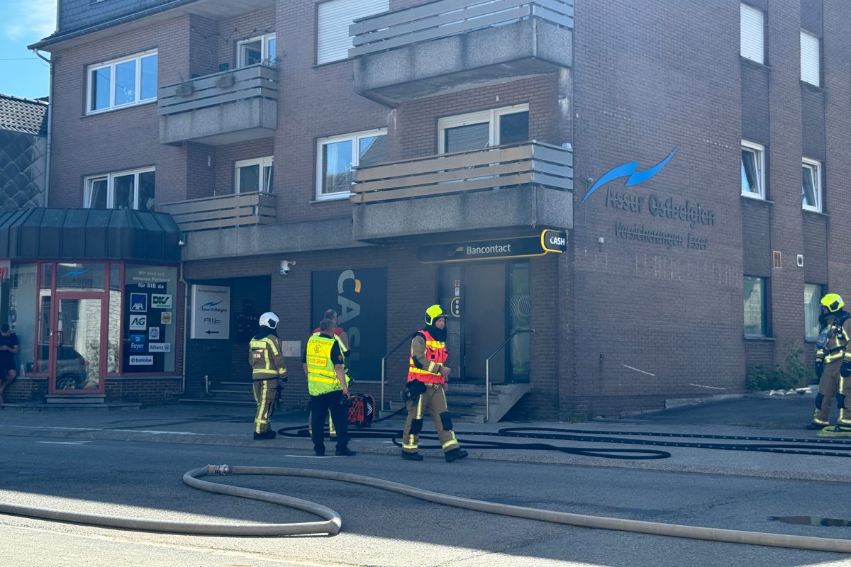 Feuerwehrleute vor der Räumlichkeit, ein Feuerwehrschlauch schlängelt sich am Boden