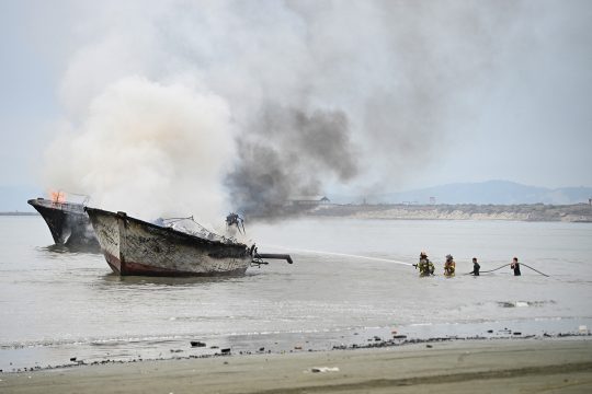 Feuerwehrleute beim Löschen brennender Boote im Hafen von Manta