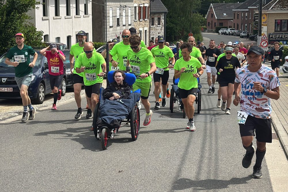 Läufer schieben ein Mädchen im Rollstuhl beim Emdygo-Lauf "Zusammen ins Ziel"