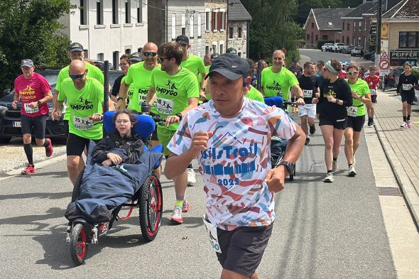 Läufer schieben ein Mädchen im Rollstuhl beim Emdygo-Lauf "Zusammen ins Ziel"
