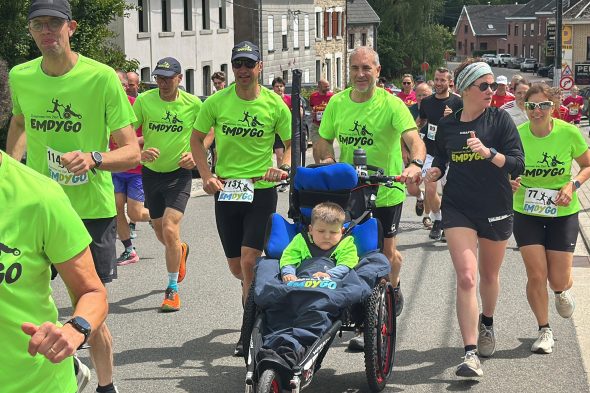 Läufer schieben einen Jungen im Rollstuhl beim Emdygo-Lauf "Zusammen ins Ziel"