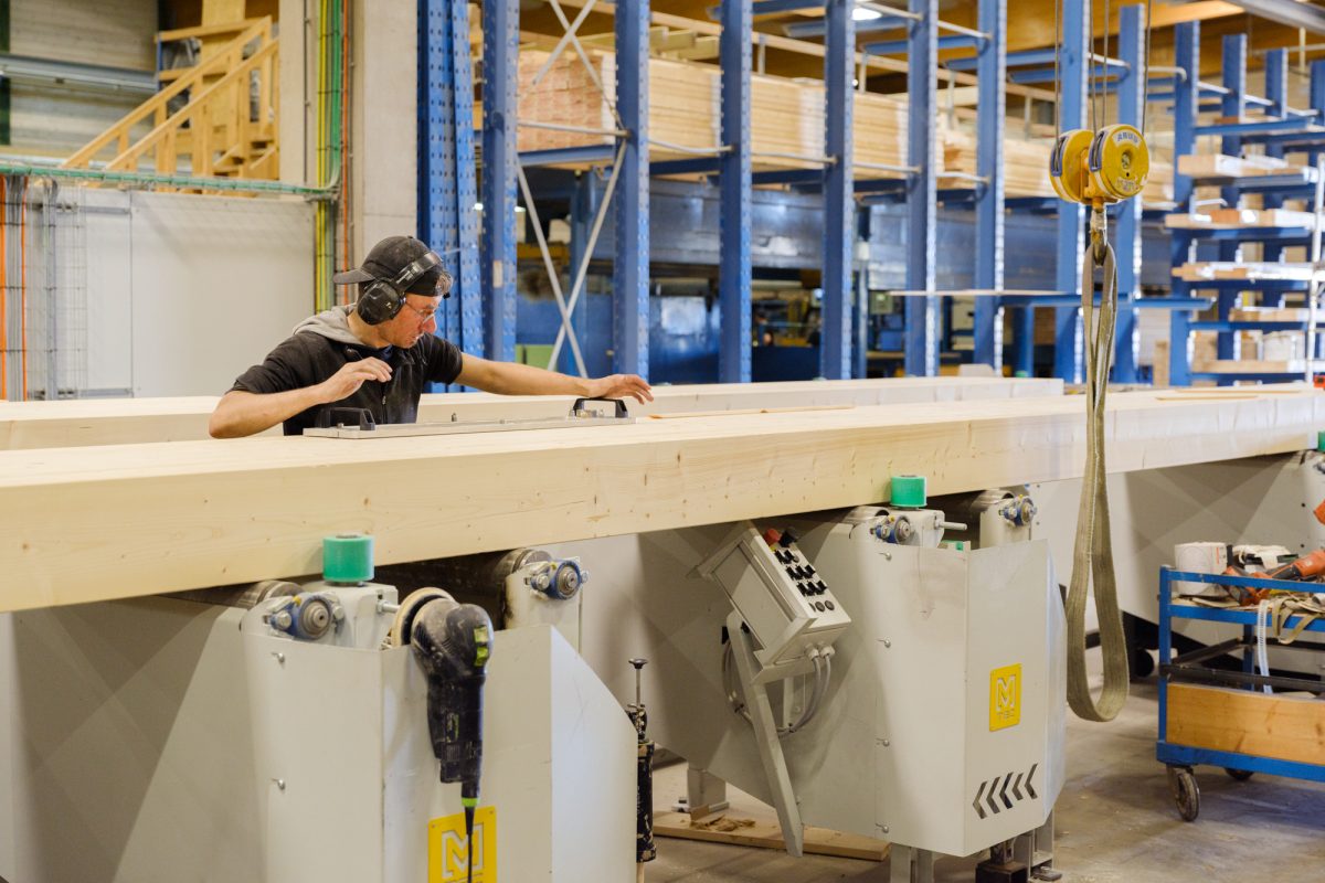 Im Sägewerk führt ein Beschäftigter Arbeiten an einem großen langen Stück Holz aus