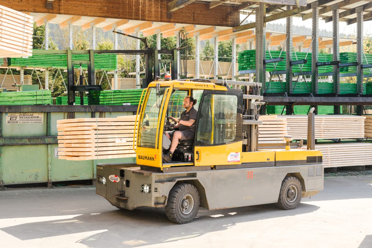 Mitarbeiter fährt mit Transportmaschine Holzbretter
