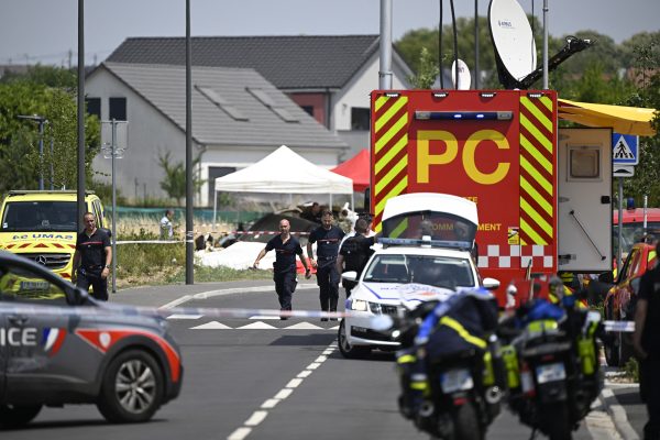 Einsatzfahrzeuge von Polizei und Feuerwehr stehen auf einer gesperrten Straße, im Hintergrund befindet sich die Absturzstelle