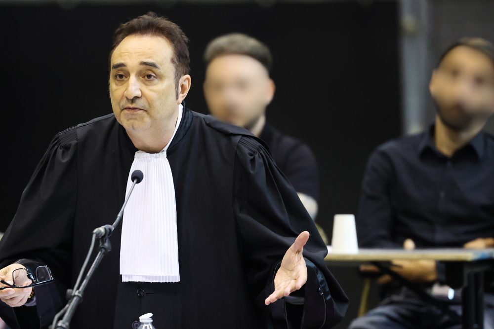 Anwalt Fabrice Guttadauria gestikuliert, im Hintergrund die Angeklagten