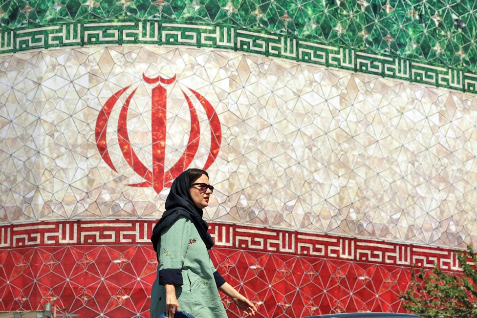 Eine Frau vor einer Plakatwand mit der iranischen Flagge