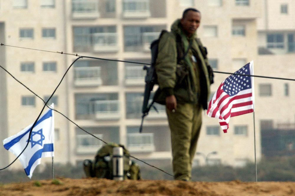 Israelischer Soldat steht zwischen einer Israel- und einer USA-Flagge