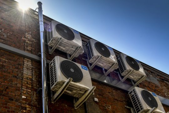 An der Fassade eines Gebäudes hängen mehrere Klimaanlagen