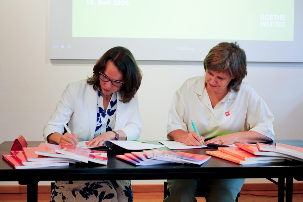 Die Leiterin des Goethe-Instituts in Brüssel, Julia Sattler, und die Vizerektorin der Universität Antwerpen, Chris Van Ginneken, unterzeichnen Dokumente