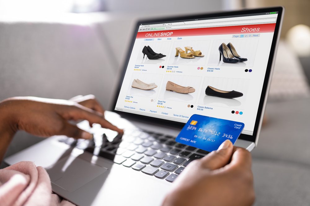 Frau hat ihre Kreditkarte in der Hand und surft am Laptop in einem Online-Shop