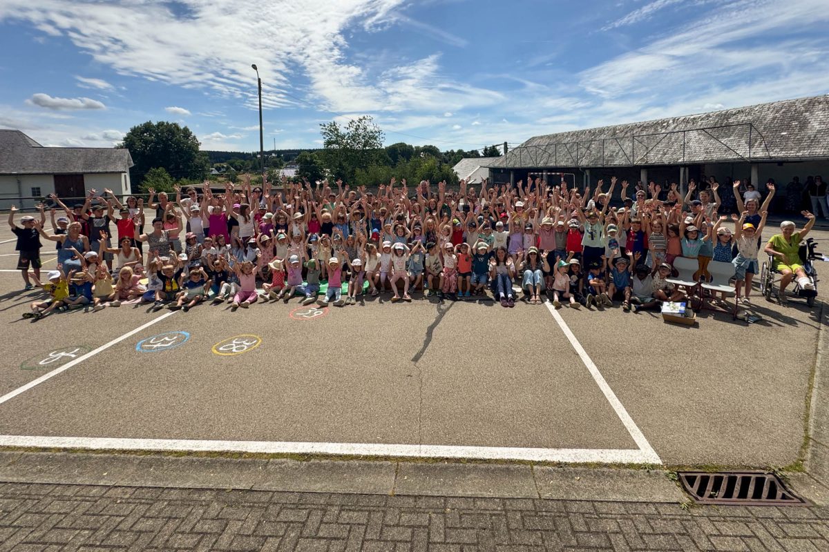Viele Schüler und Lehrer sitzen und stehen auf dem Schulhof, um ihren Schulleiter zu feiern