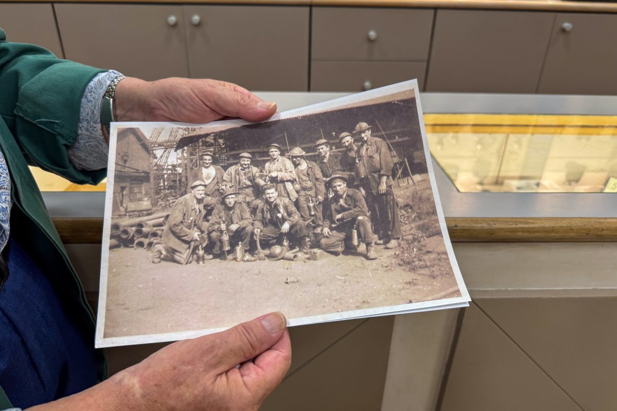 Sante hält ein altes Schwarz-Weiß-Foto von Bergarbeitern in den Händen