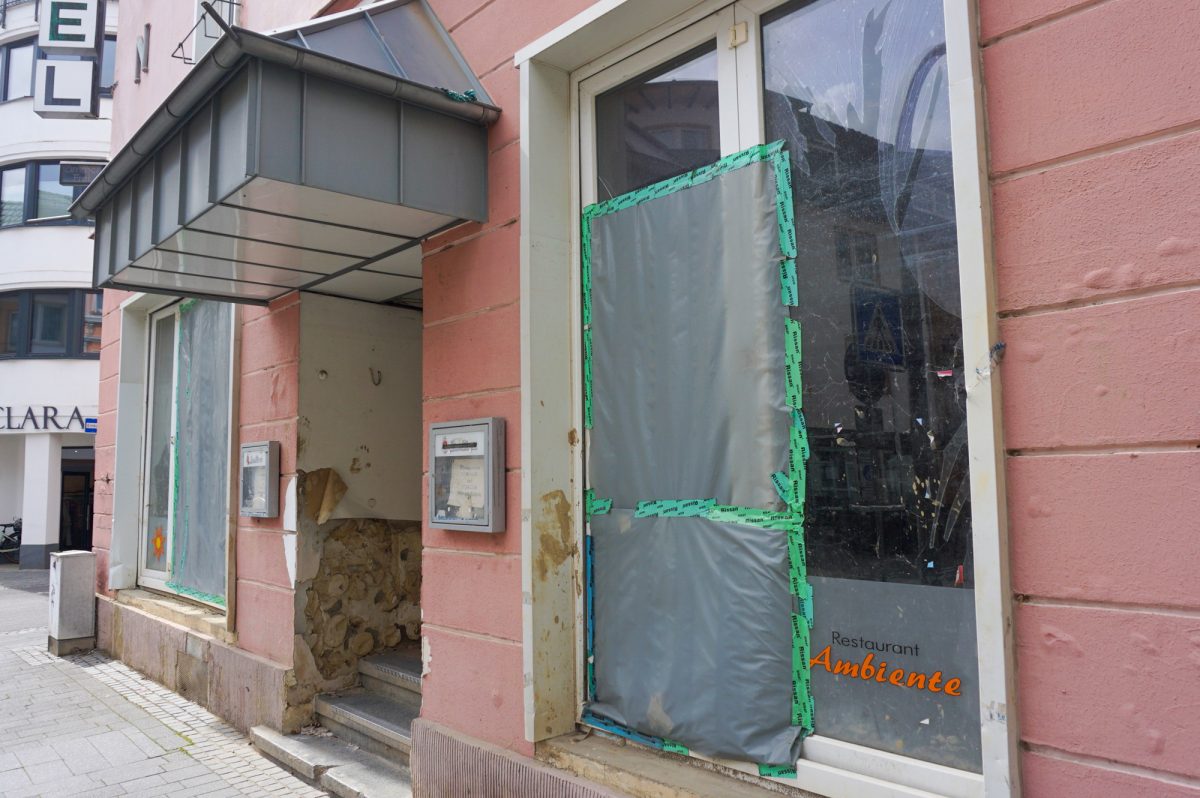Gebäude mit Plane auf kaputter Fensterscheibe und Schlammspuren an der Fassade