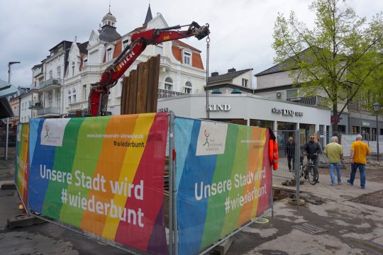 Hinter einer Baustellenabsperrung steht ein Bagger