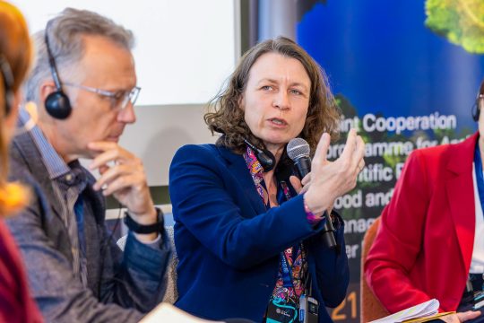 Cornelia Weigand spricht bei einer Konferenz in ein Mikrofon