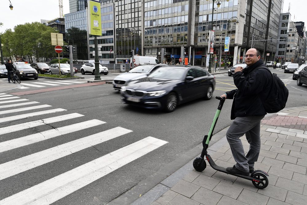 Mann mit E-Roller steht an Zebrastreifen in Brüssel