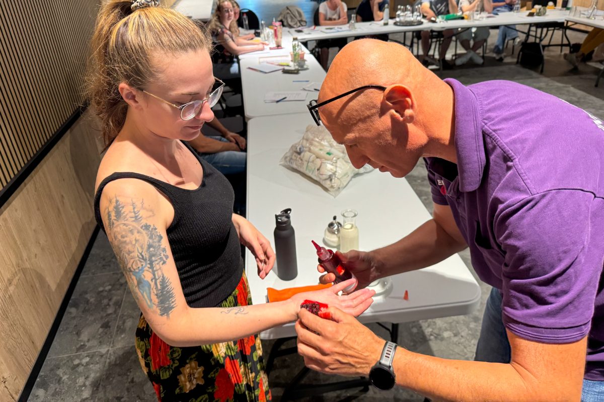 Eine Mitarbeiterin bekommt Kunstblut auf die Hand getröpfelt