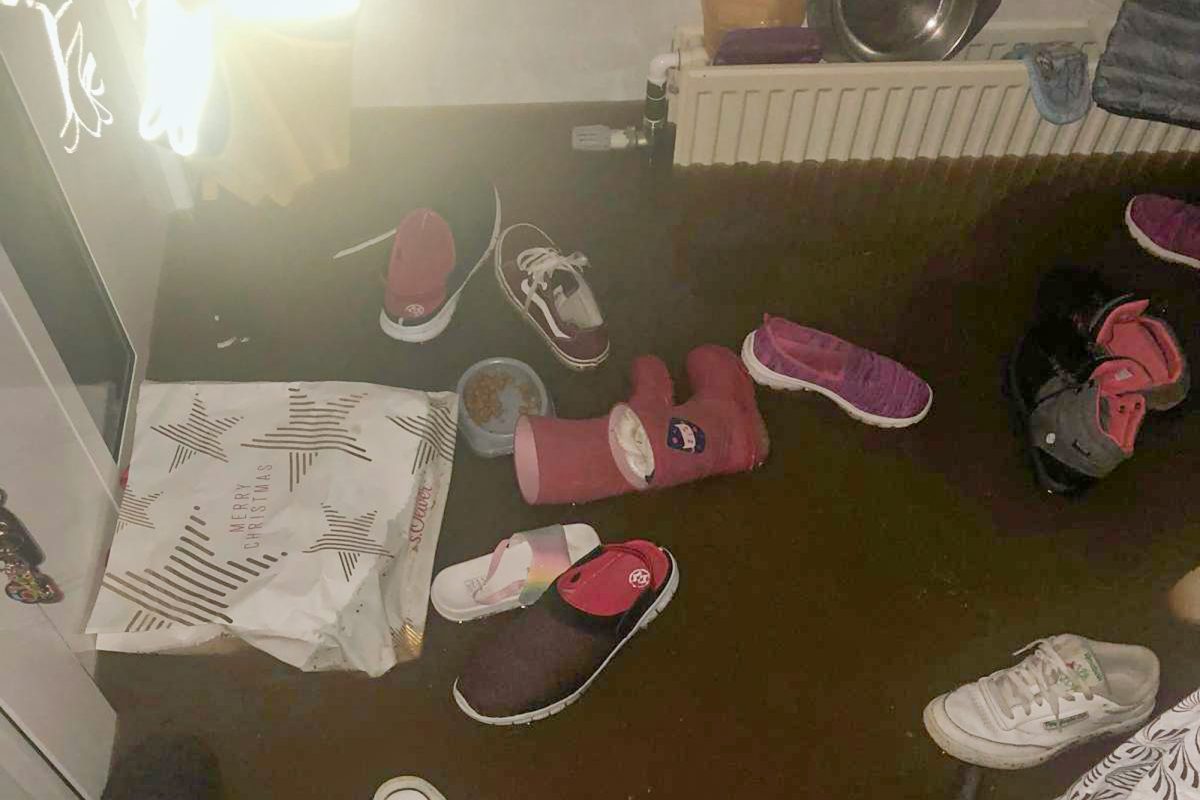 Wasser steht im Wohnraum, darin schwimmen Schuhe