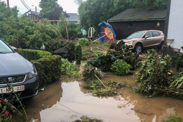 Der Garten steht unter Wasser, im Hintergrund ein Auto und ein weggeschwemmter Sonnenschirm
