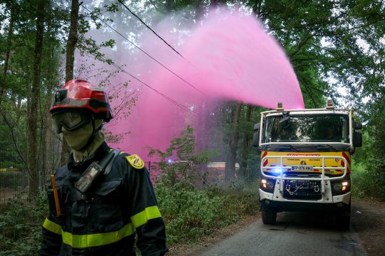 Ein Löschfahrzeug versprüht im Wald von Fontainebleau ein pinkfarbenes Feuerhemmungsmittel